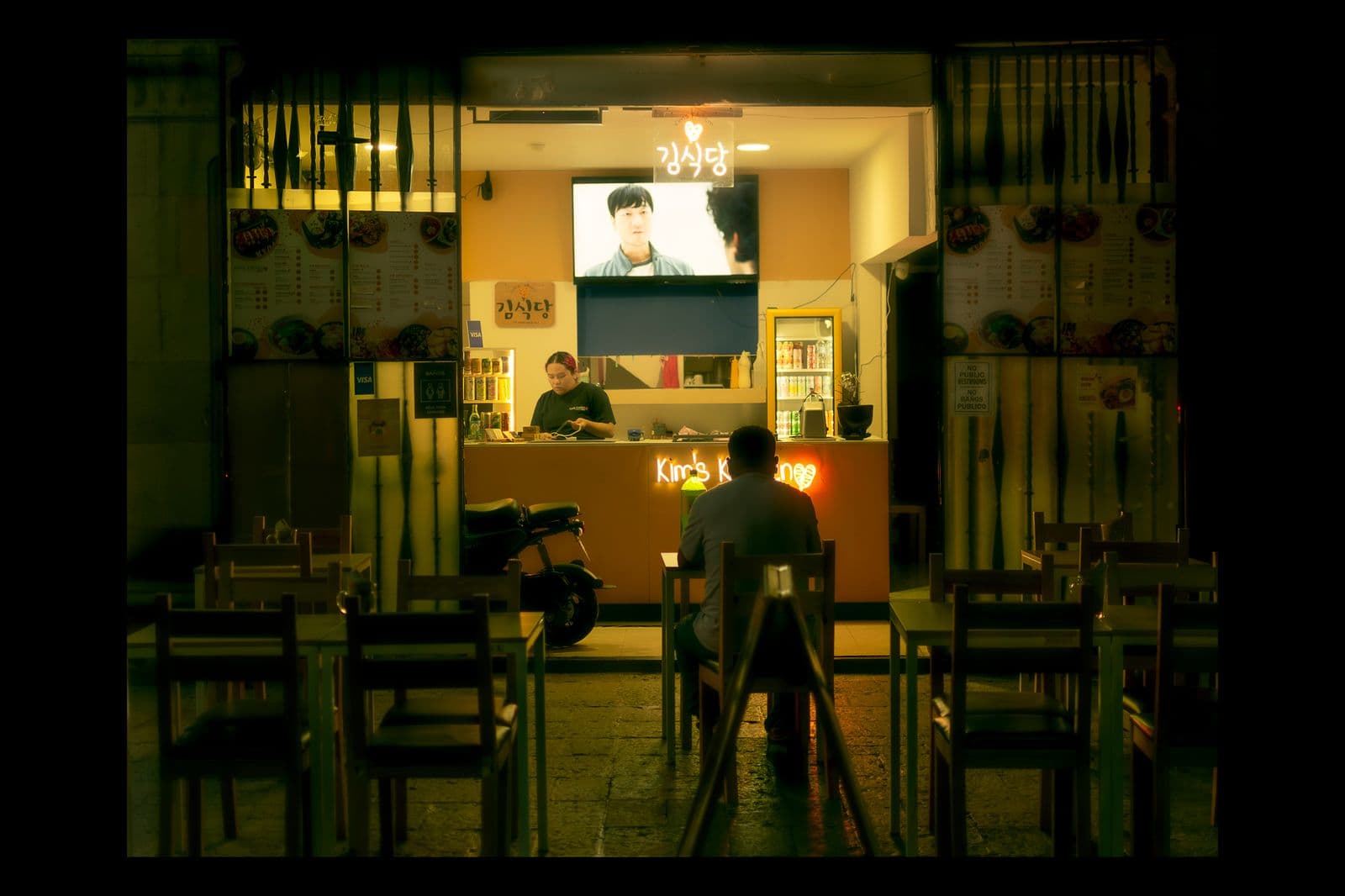 A wall-mounted TV playing above the seating area of a neighborhood bar, a typical commercial mounting setting